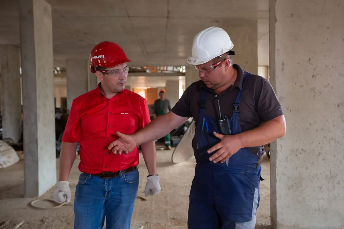 Zwei Handwerker mit Schutzhelm besprechen sich auf einer Baustelle
